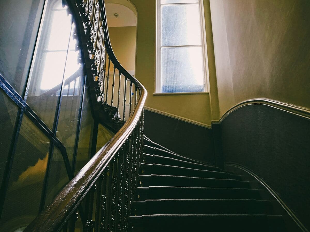 Une cage d’escalier avec sa rampe, dans une maison ancienne